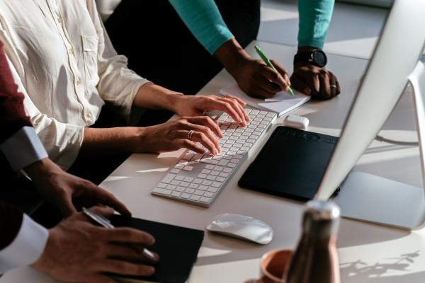 Office workers gathering around a laptop computer